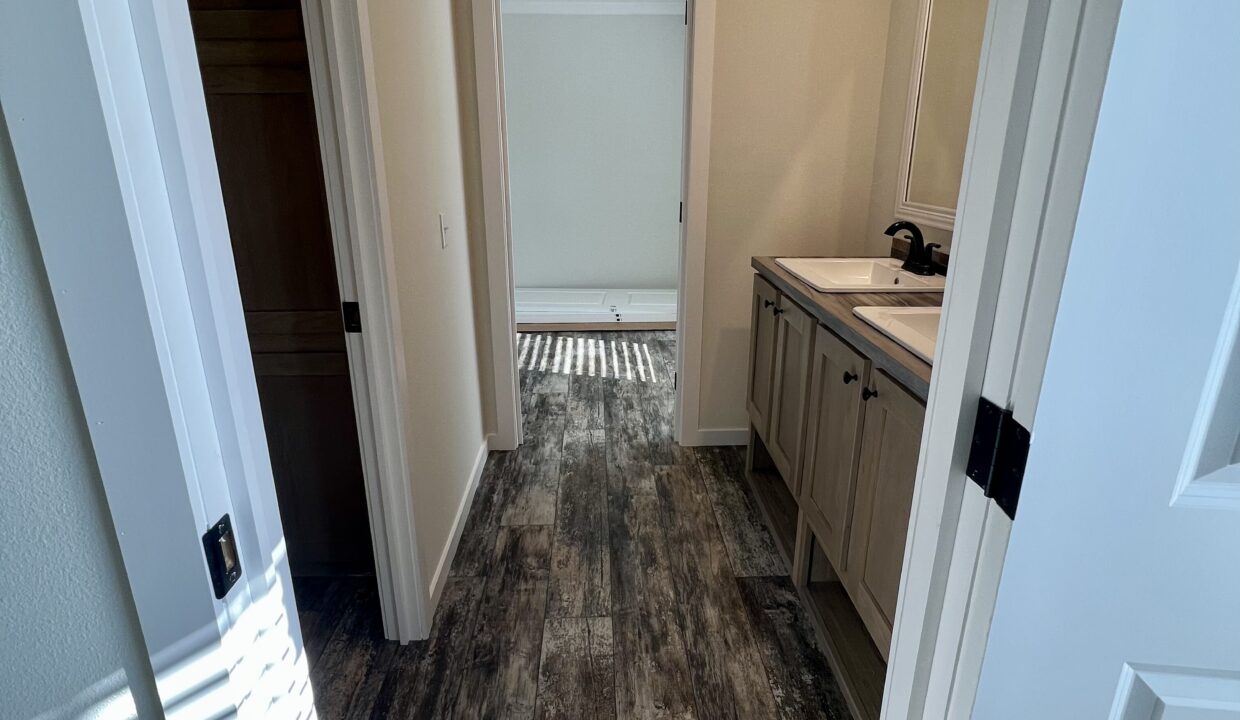 Interior view of the Boujee XL manufactured home featuring a spacious bathroom with dual sinks, modern fixtures, and stylish flooring.