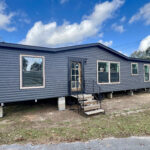 Exterior view of the Bandit manufactured home by Clayton Homes, featuring a modern design, multiple windows, and a front staircase, highlighting its appeal for potential buyers.