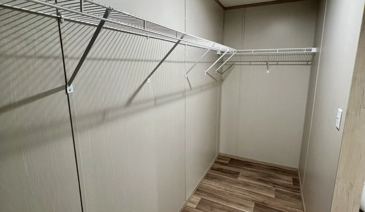 Spacious closet interior featuring wire shelving and wood-style flooring, showcasing storage options in the Snowcap manufactured home by Sanders Housing.